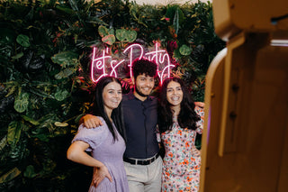 people posing in front of a tropical flower wall for a photo booth photo in christchurch